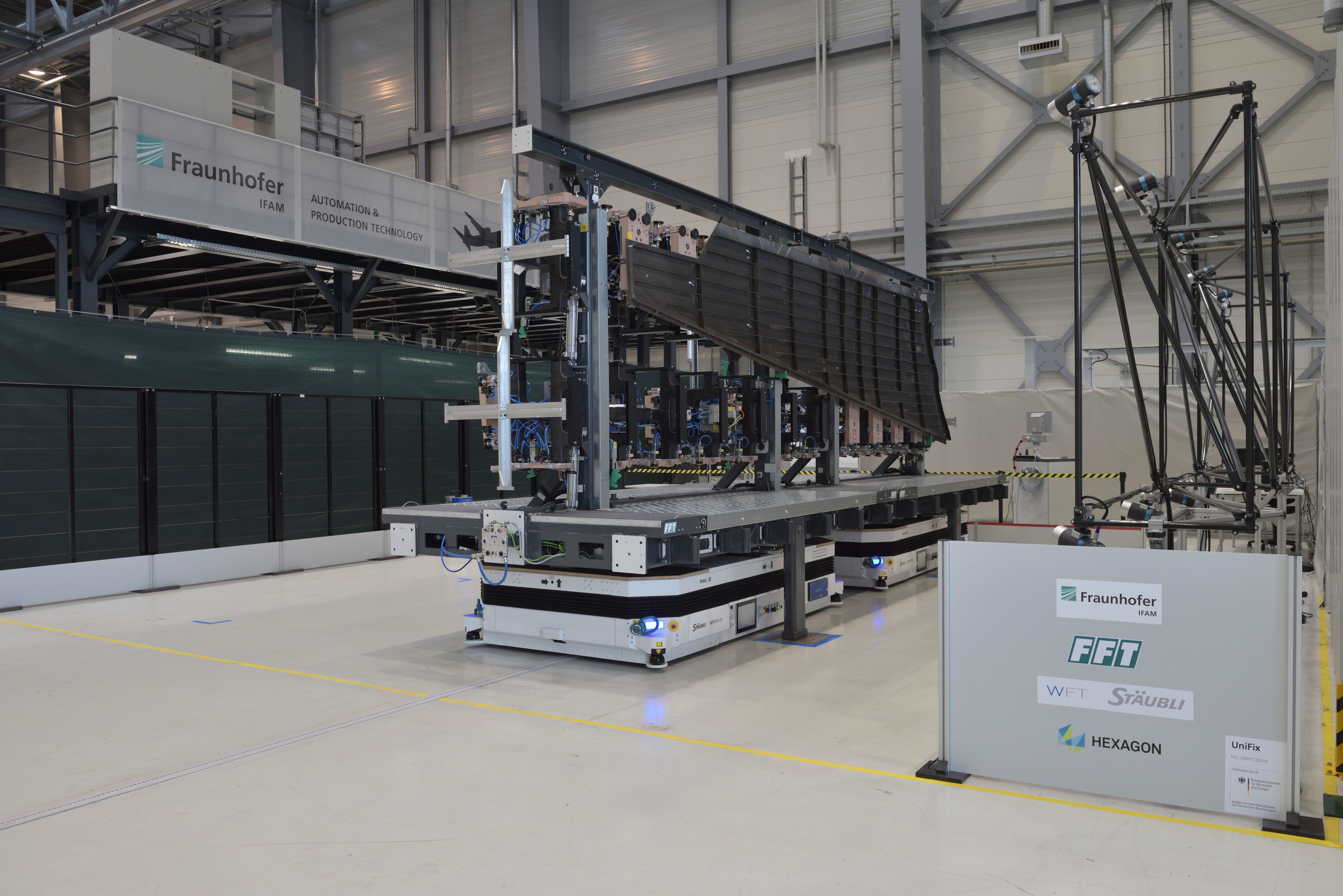 Die erste Station der »UniFix«-Flow-Line: Das neu entwickelte, durch virtuell gekoppelte AGV-Systeme mobile Spannfeld transportiert das exakt positionierte CFK-Seitenleitwerk-Schalenelement in die Kamera-Arena, wo die Formhaltigkeit des Spannfelds überprüft wird