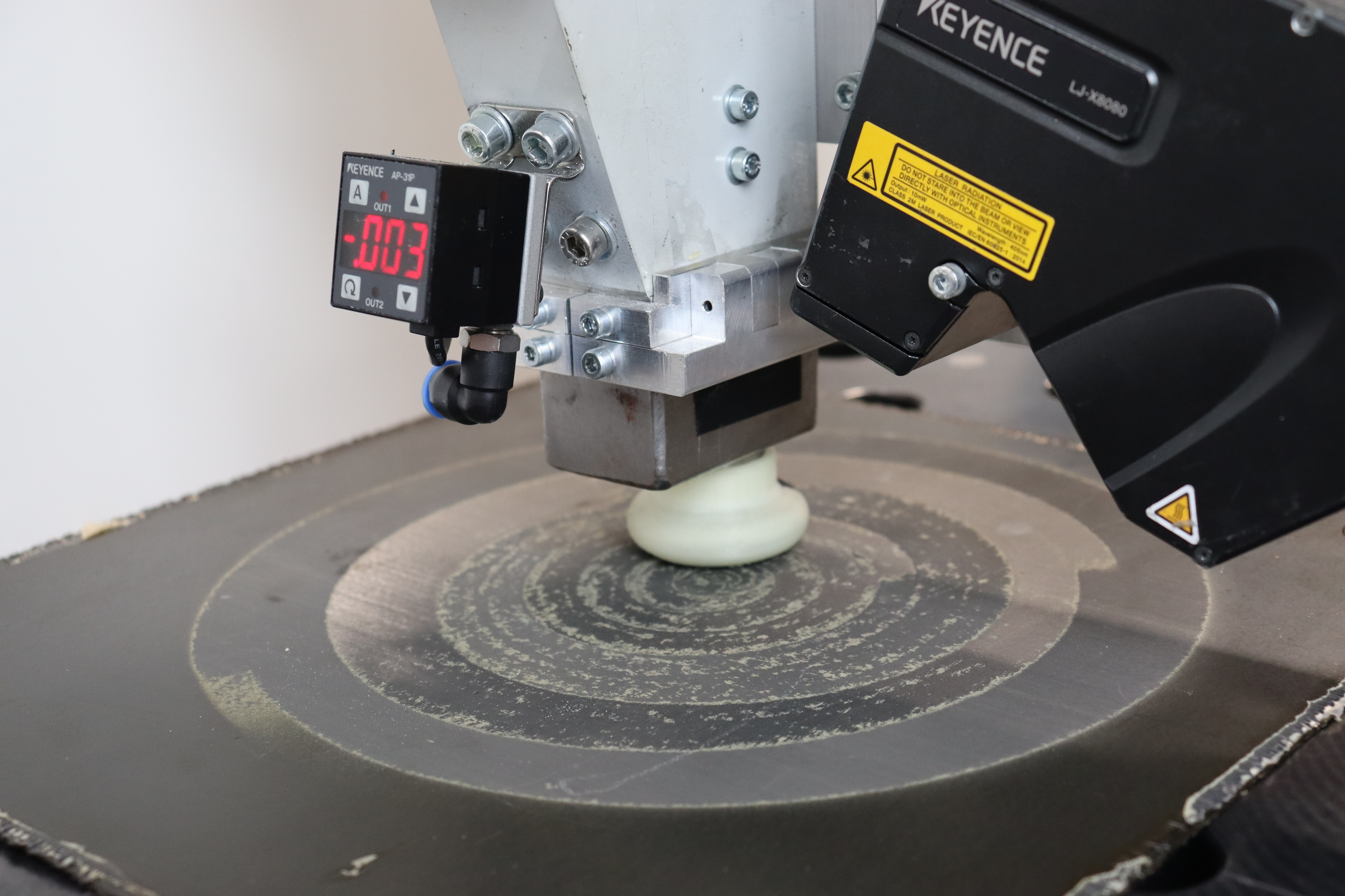 The robotically guided vacuum suction blasting nozzle – developed at Fraunhofer IFAM in Stade – during the scarfing and activation of a CFRP component. The robotically guided vacuum suction blasting nozzle – developed at Fraunhofer IFAM in Stade – during the scarfing and activation of a CFRP component.