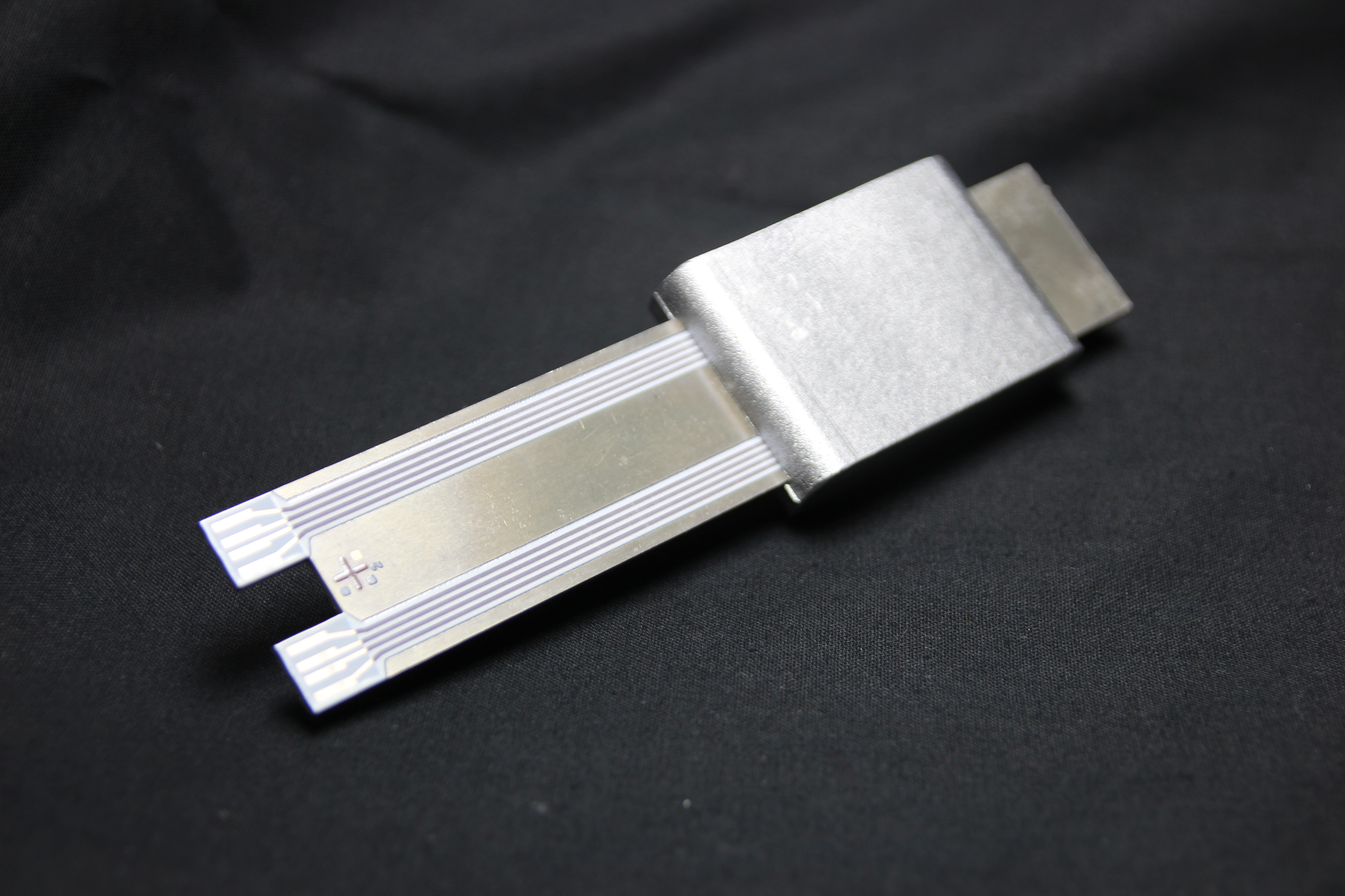Section of a low-pressure die-cast component with integrated strain and temperature sensors produced using thick-film technology